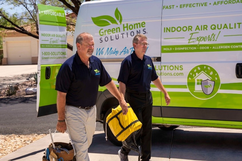 iStock-1351320964 Two men in branded Green Home Solutions uniforms walk beside a branded truck with a yellow work bag.