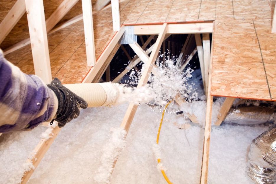 attic insulation being blown through a tube into an attic