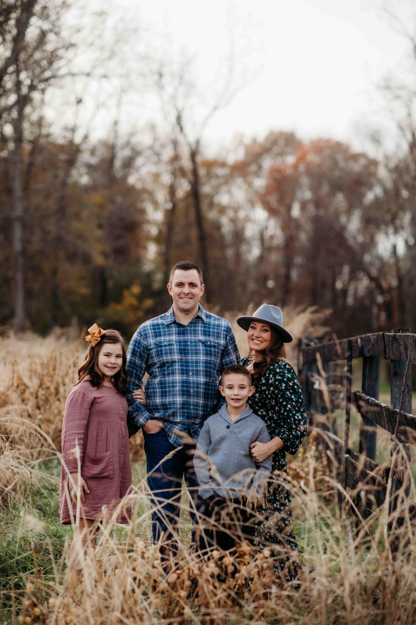 Family photo of mom, dad, son, and daughter posing near a fence