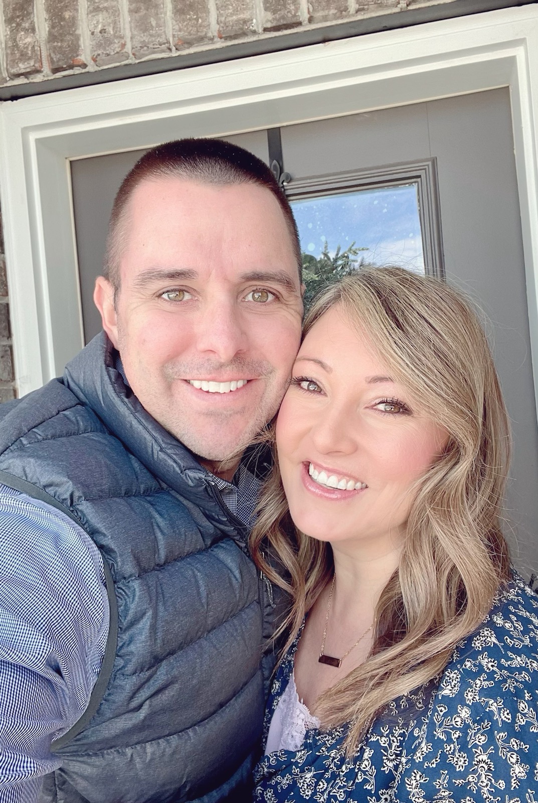 husband and wife smiling at front door