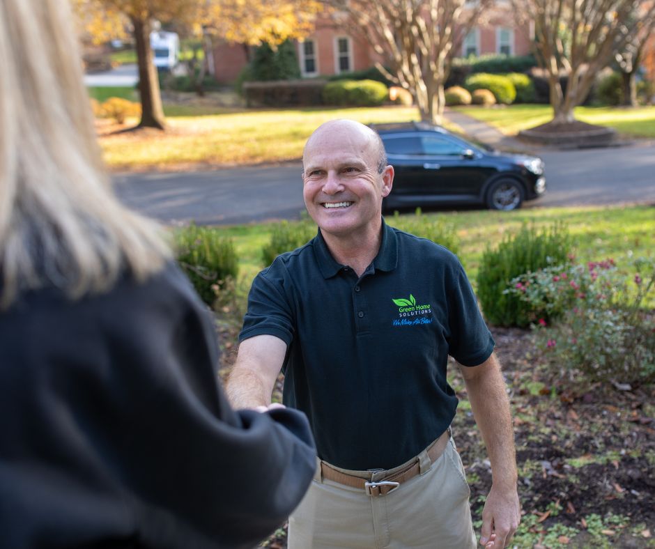 man in black shirt greeting a woman on her front porch and shaking her hand.