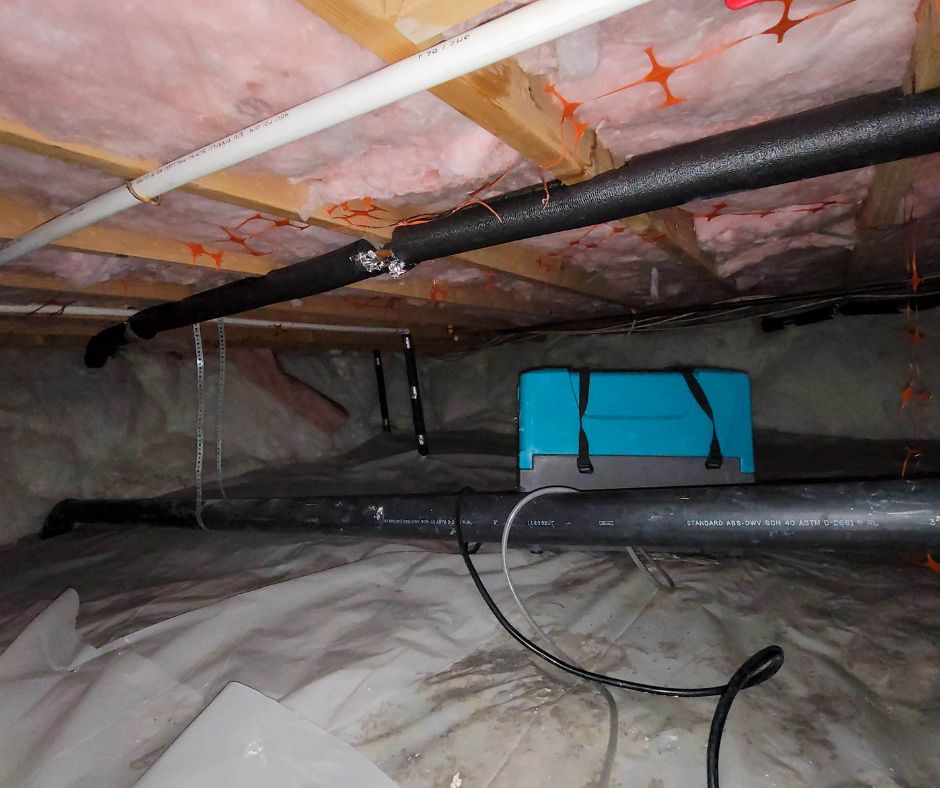 crawl-space-encapsulation-service-vapor-barrier a dehumidifier in a crawl space under wet pink insulation