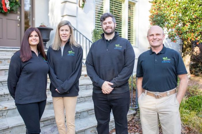 green-home-solutions-indoor-air-quality-crawl-space-experts two men and two women in black jackets standing in front of a house