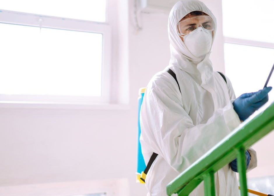 man in white hazmat suit spraying a disinfection solution with a wand