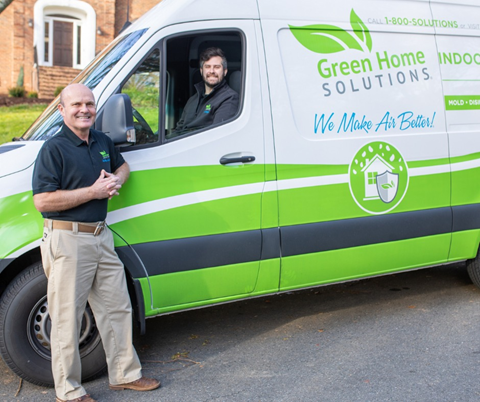A Green Home Solutions Employee in the Driver Seat of a GHS Van and Another Outside of it Leaning Against the Side Smiling