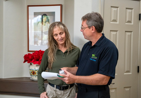 A Green Home Solutions Technician A Woman Sits at a Desk with an Open Laptop and Leans Back with Her Eyes Closed and Arms Behind Her Head Taking a Deep Breath