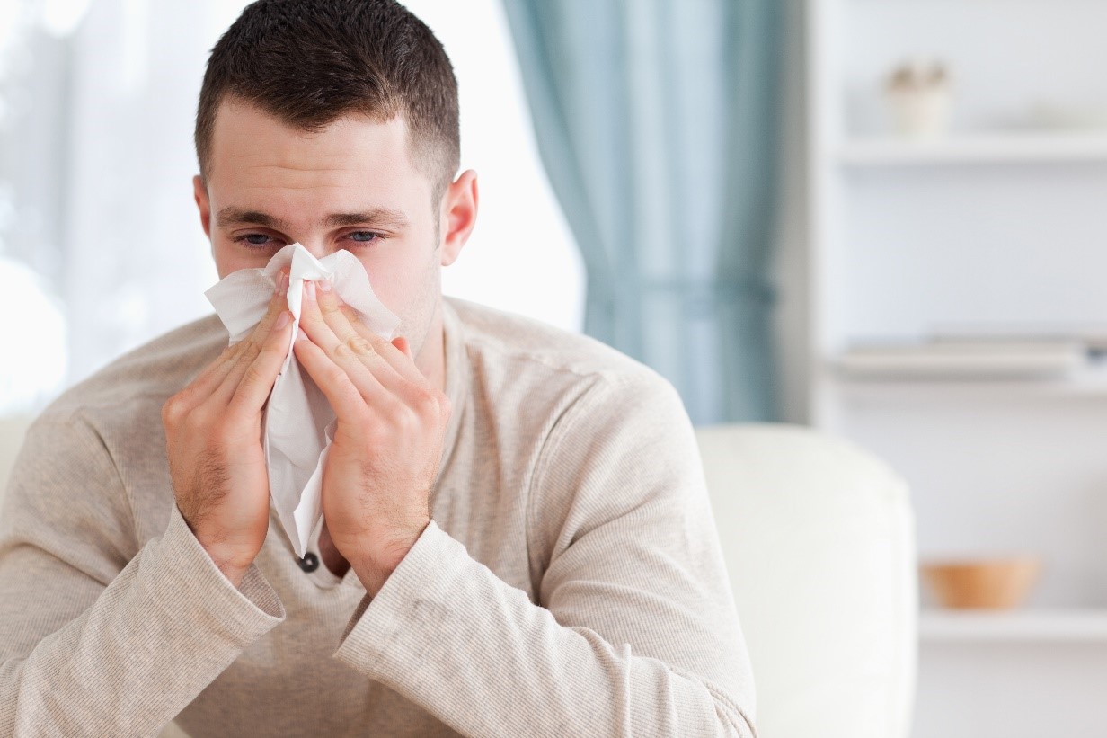 A Man in a Beige Long-Sleeve Shirt Blowing His Nose into a Tissue A Man in a Beige Long-Sleeve Shirt Blowing His Nose into a Tissue