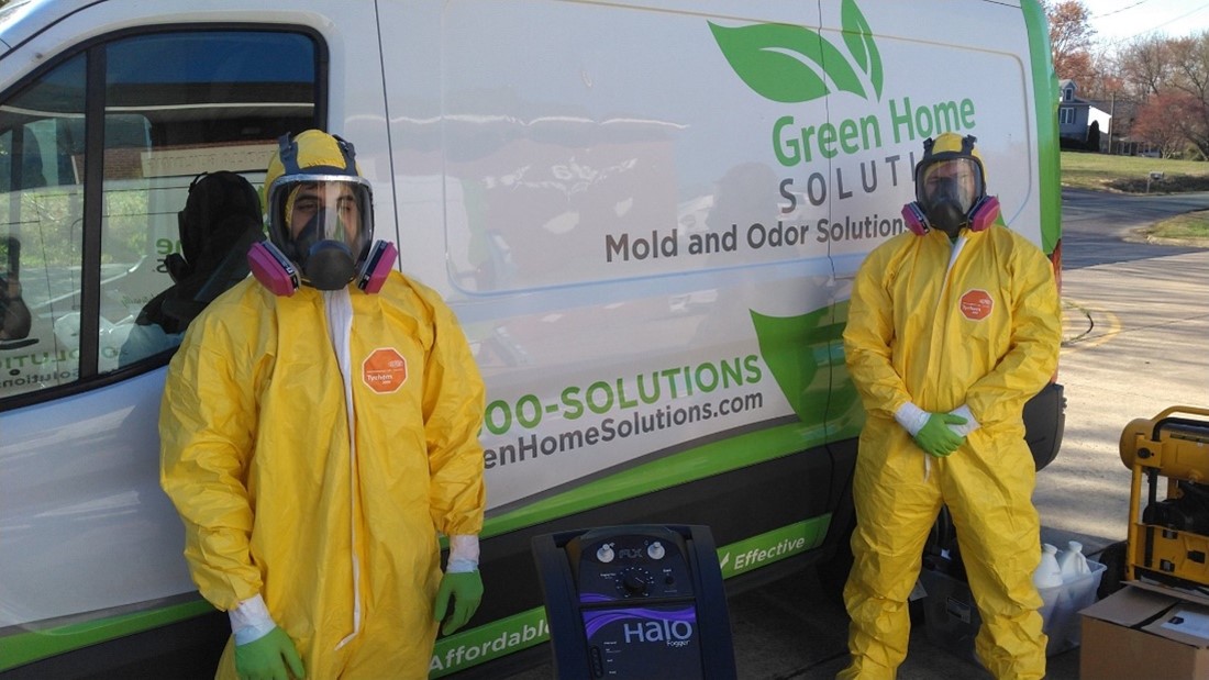 Two Green Home Solutions Employees in PPE Standing Two Green Home Solutions Employees in PPE Standing in Front of a GHS Van with a Disinfection Treatment Fog Machine Between Them