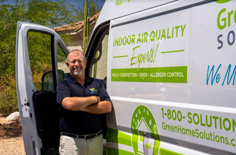 A Man in a Green Home Solutions Polo Stands Next to an Open Van Door with Green Home Solutions Graphics on the Vehicle