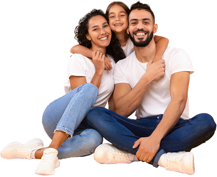 A Smiling Mother and Father in White Shirts and Jeans Sitting While Their Daughter Embraces Them from Behind 