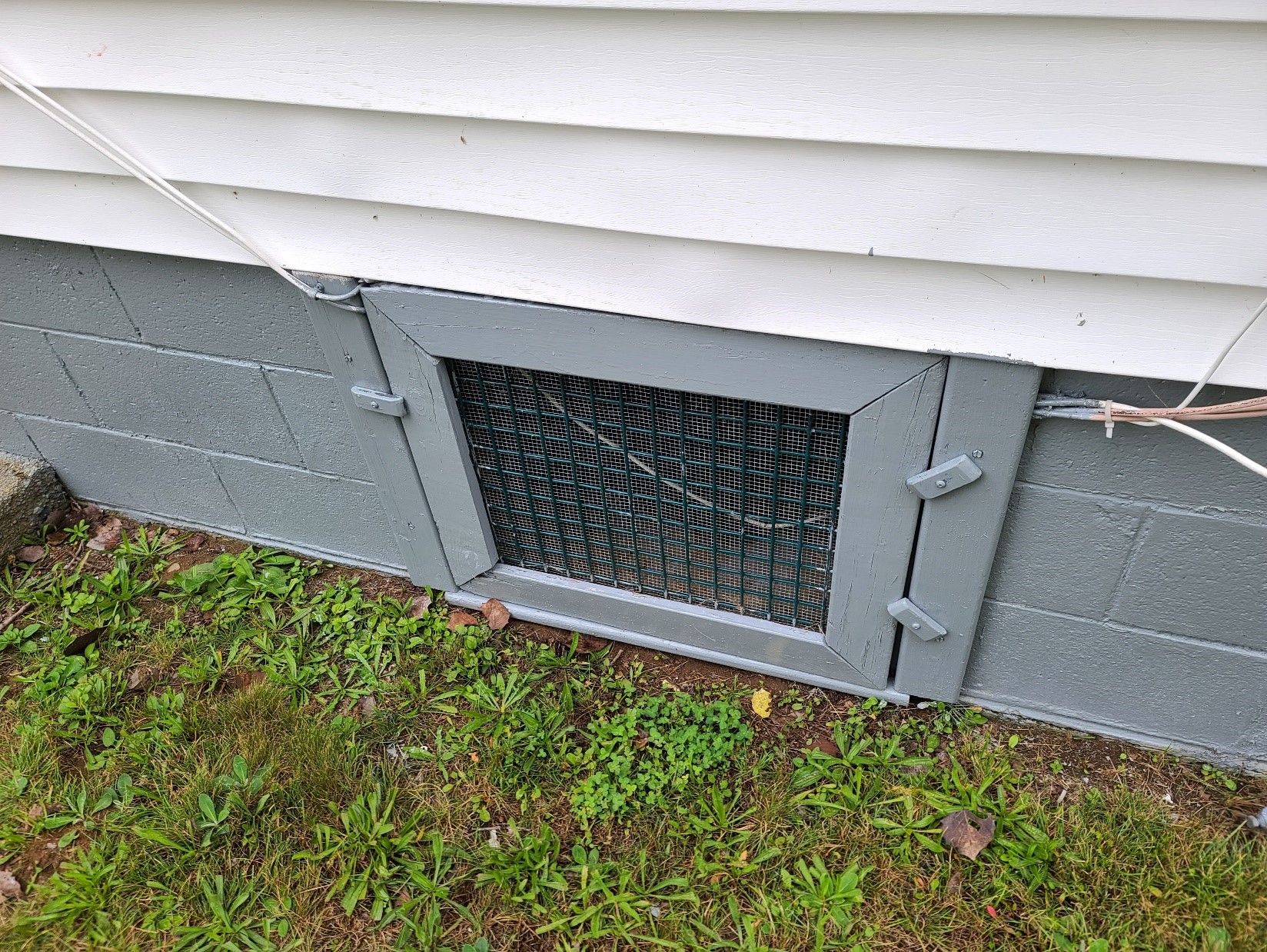 A small gate that opens to a crawl space beneath a home. 