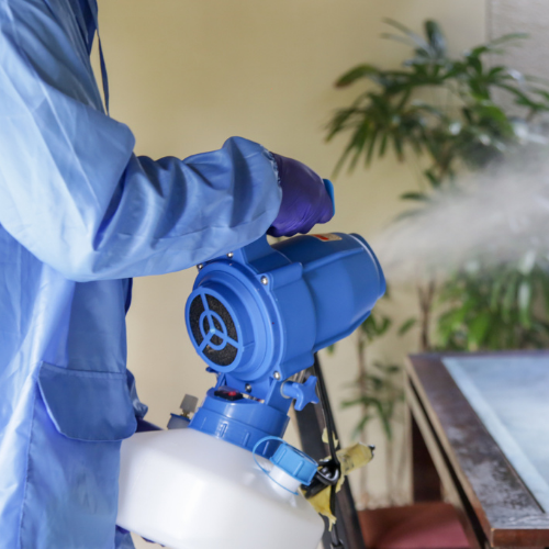 man spraying basement waterproofing mixture from a pump sprayer in a basement of a home