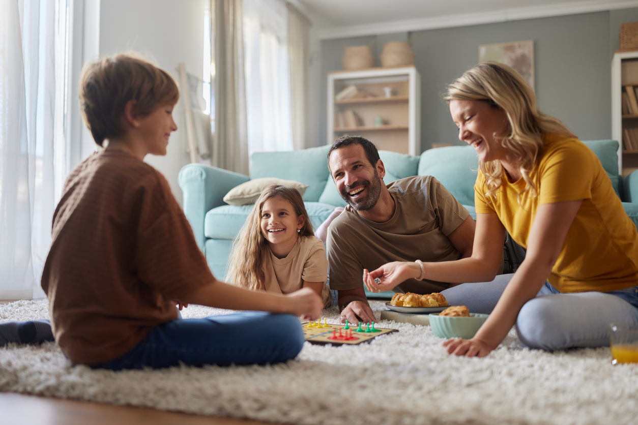 green-home-solutions-indoor-air-quality Happy parents and their kids playing Ludo on carpet at home.